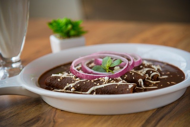 Rich mole poblano enchiladas with purple onions and crema